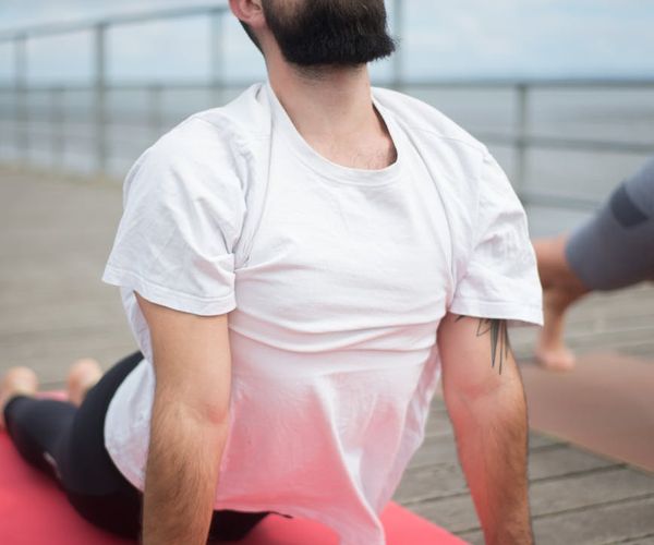 Man stretching on a yoga mat, focusing on flexibility and mental calm.